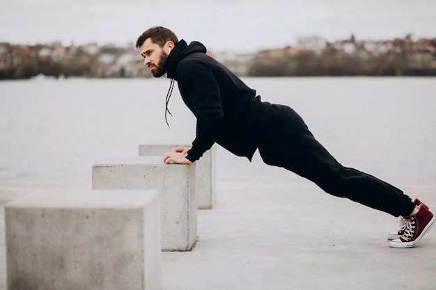 Młody sportowy mężczyzna ćwiczy rzeką i robi push up