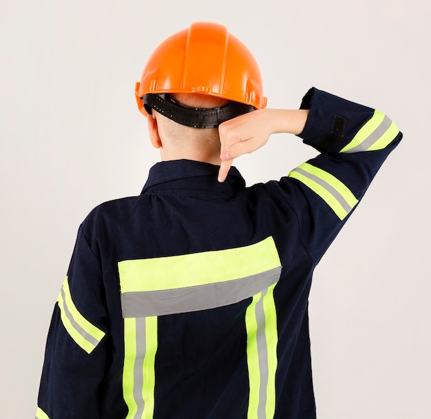 Młody strażak wskazuje przy mundurem