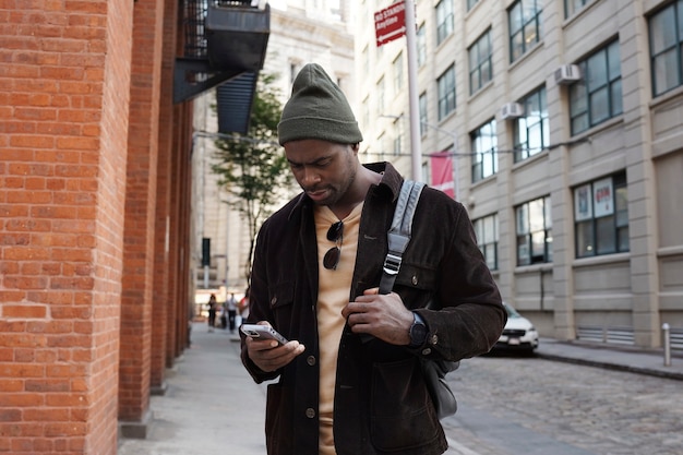 Bezpłatne zdjęcie młody stylowy mężczyzna zwiedzający miasto podczas korzystania ze smartfona