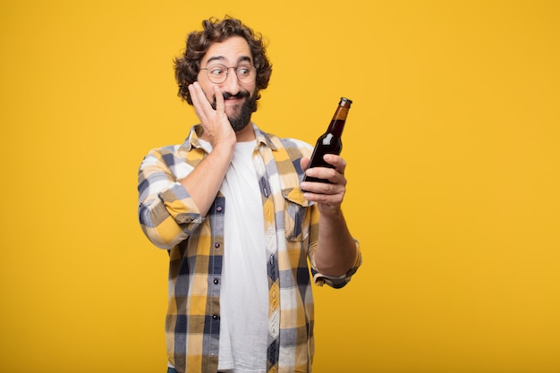 Młody szalony szalony człowiek pozować z butelką piwa.