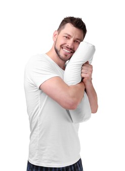 Młody szczęśliwy człowiek w piżamie przytulający ortopedyczną poduszkę na białym tle