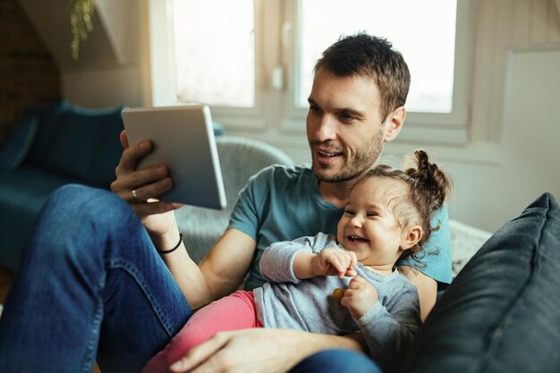 Młody szczęśliwy ojciec i córka bawią się podczas robienia selfie z cyfrowym tabletem w domu