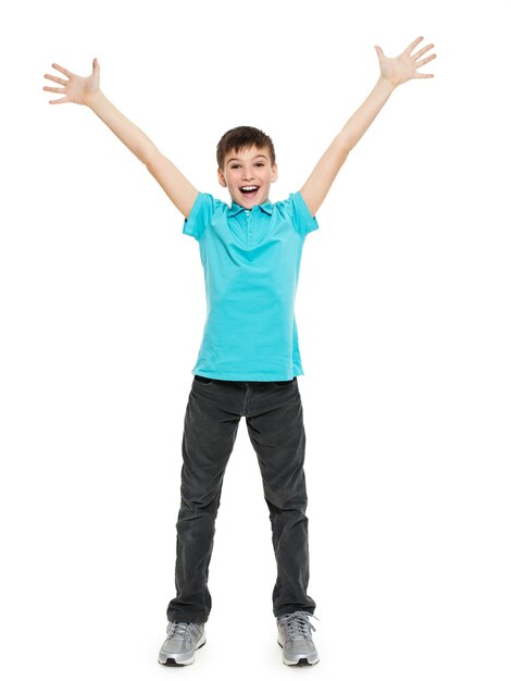 Młody szczęśliwy teen chłopiec zw przypadkowych z podniesionymi rękami do góry na białym tle.