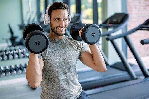 Młody szczęśliwy wysportowany mężczyzna ma trening siłowy w klubie fitness