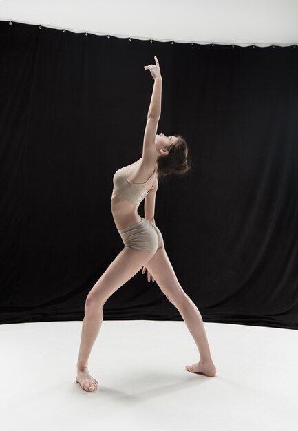 Młody tancerz nastolatek taniec na tle studio białym piętrze. Projekt Ballerina.