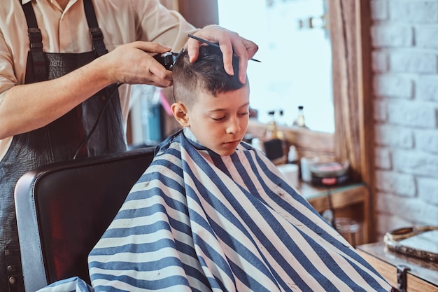 Bezpłatne zdjęcie młody uczeń dostaje modną fryzurę od doświadczonego fryzjera w nowoczesnym zakładzie fryzjerskim.