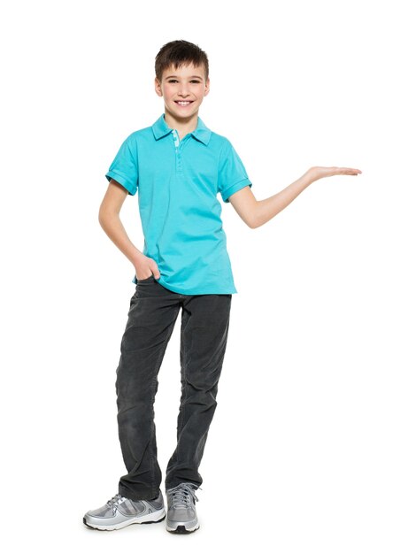 Młody uśmiechnięty chłopiec teen pokazuje coś na dłoni na białym tle.