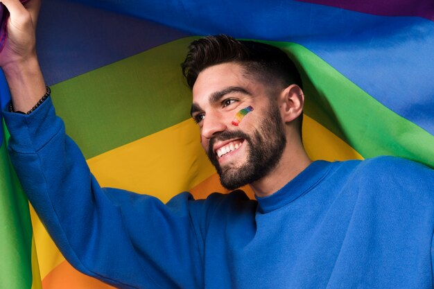 Młody uśmiechnięty mężczyzna z LGBT tęczy flaga