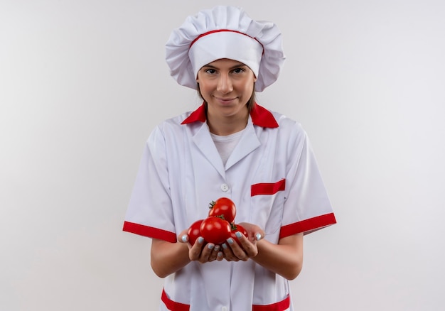Młody zadowolony kucharz kaukaski dziewczyna w mundurze szefa kuchni trzyma pomidory na rękach na białym z miejsca na kopię