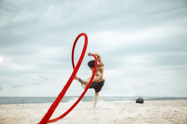 Młody zdrowy mężczyzna sportowiec robi przysiady na plaży