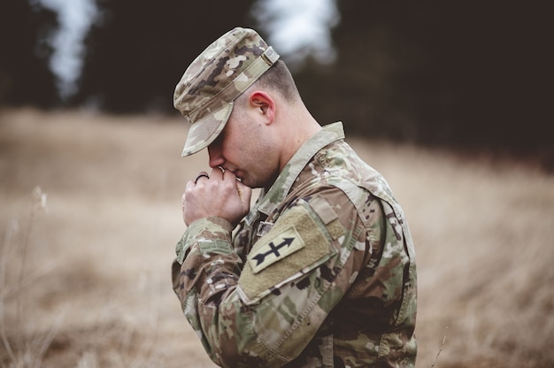 młody żołnierz modląc się na polu