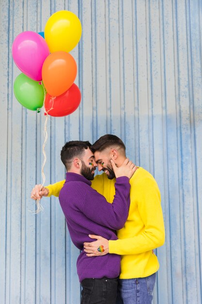 Młodzi homoseksualiści z stubarwnymi balonami ściska na ulicie