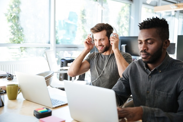 Młodzi koledzy siedzący w biurze coworking