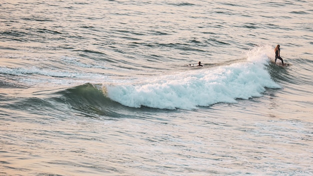 Młodzi ludzie surfują na morzu w słoneczny dzień