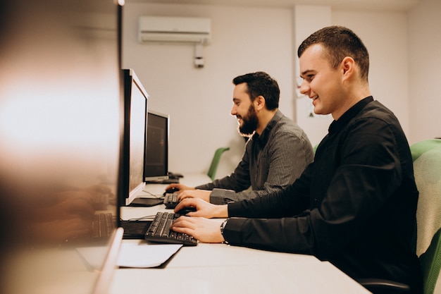 Bezpłatne zdjęcie młodzi męscy projektanci stron internetowych pracujący na komputerze