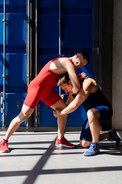 Bezpłatne zdjęcie młodzi mężczyźni w strojach sportowych demonstrujący walkę zapaśniczą