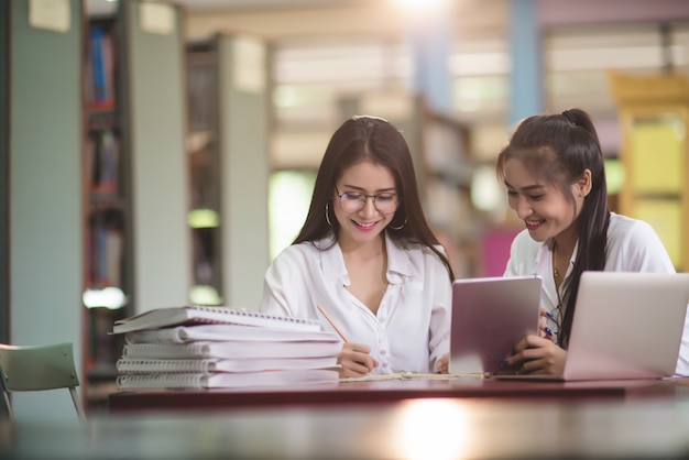 Młodzi studenci uczący się, regały biblioteczne