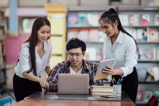 Młodzi studenci uczący się, regały biblioteczne