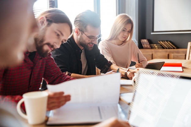 Młodzi szczęśliwi koledzy siedzi w biurowym coworking