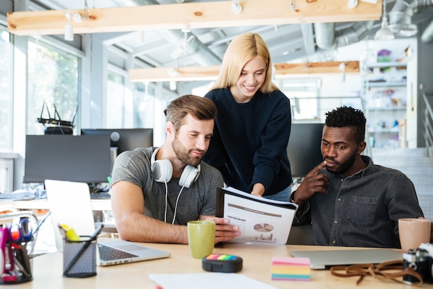 Młodzi szczęśliwi koledzy siedzi w biurowym coworking