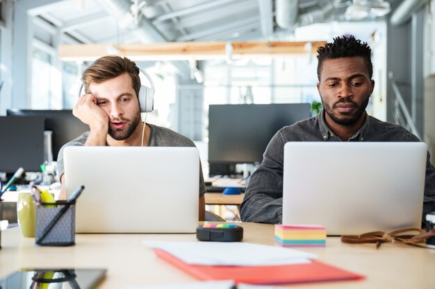 Młodzi zmęczeni koledzy siedzący w biurze coworking