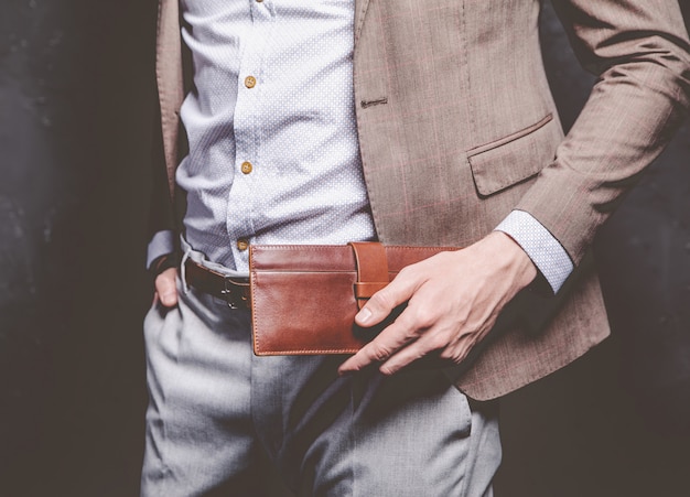 Bezpłatne zdjęcie moda piękny portret młodego biznesmena przystojny model mężczyzna ubrany w elegancki brązowy garnitur z akcesoriami