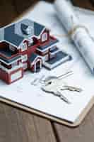 Bezpłatne zdjęcie model domu willi, klucz i rysunek na desktopie retro (koncepcja sprzedaży nieruchomości)