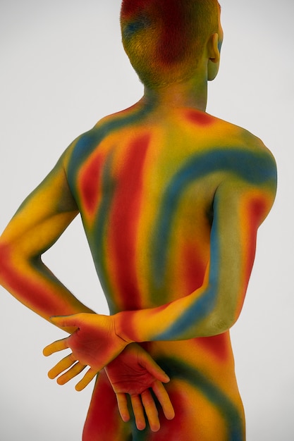 Bezpłatne zdjęcie model mężczyzna pozuje z kolorowym malowaniem ciała