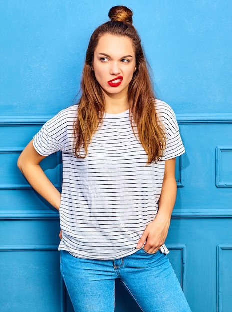Model młoda kobieta stylowa w letnie ubrania z czerwonymi ustami, pozowanie w pobliżu niebieską ścianą