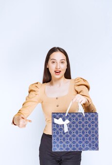 Model piękna kobieta trzyma torbę na zakupy z kokardą.