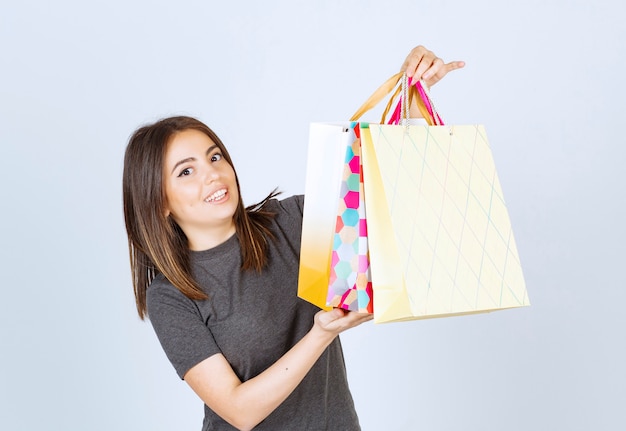 Model szczęśliwa kobieta trzyma wiele toreb na zakupy na białym tle.