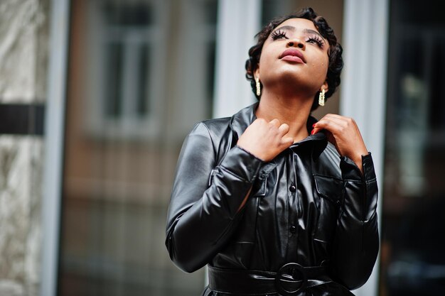 Modna piękna afroamerykanka pozuje w czarnej skórzanej kurtce na ulicy