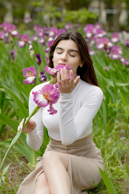 Modna szczupła dziewczyna trzymająca kwiat pachnąca z zamkniętymi oczami, podziwiająca przyjemność