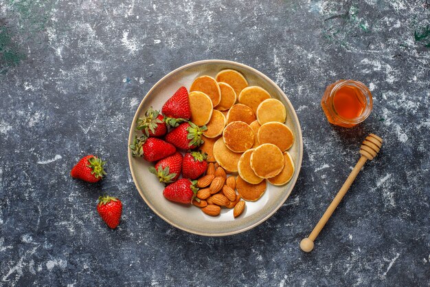 Modne jedzenie - mini pancake płatki. Sterta naleśników zbożowych z jagodami i orzechami.