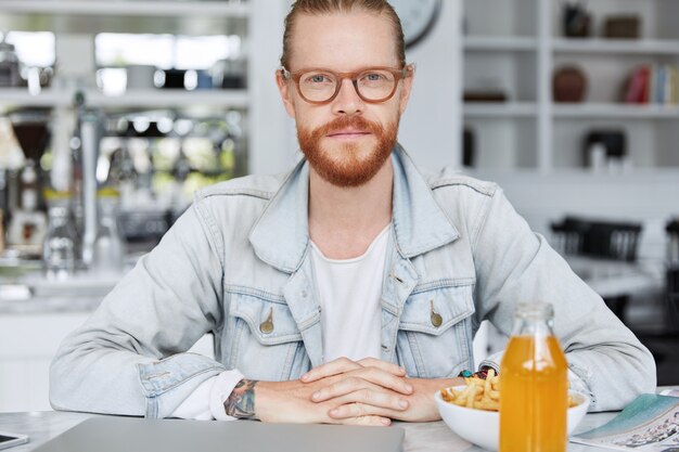 Modny hipster facet ubrany w dżinsową koszulę i stylowe okulary