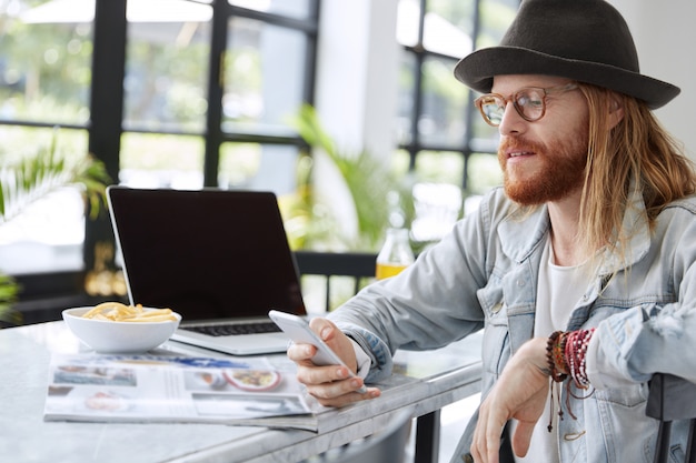 Modny hipster facet ubrany w stylowy czarny kapelusz i dżinsową koszulę