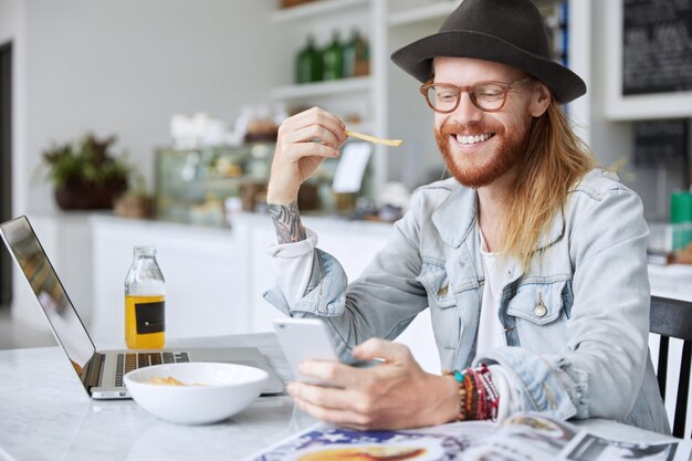 Modny hipster facet ubrany w stylowy czarny kapelusz i dżinsową koszulę