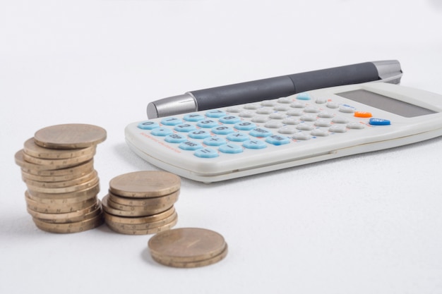 Bezpłatne zdjęcie monety obok kalkulatora i pióra