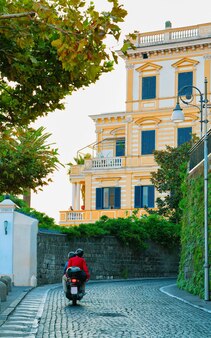 Motocykl na ulicy w luksusowym porcie marina grande w sorrento niedaleko neapolu na morzu tyrreńskim, wybrzeże amalfi, włochy. motorower we włoskim letnim raju. linia brzegowa skuterów i amalfitany.