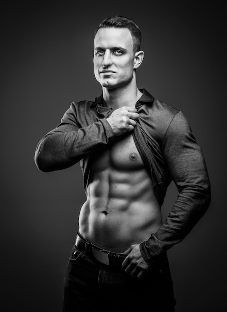 Muskularny facet pozuje pokazując swoje mięśnie brzucha i muskularne ciało