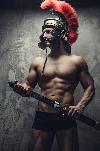 Bezpłatne zdjęcie muskularny mężczyzna w wojennym hełmie i mieczu.