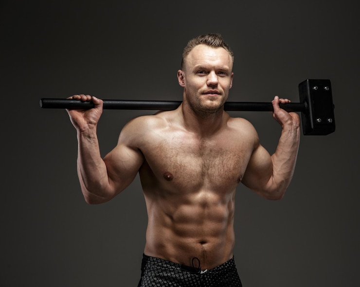 Bezpłatny plik Zdjęcie muskularny mężczyzna z nagim torsem trzyma duży hummer. na białym tle na szarym tle