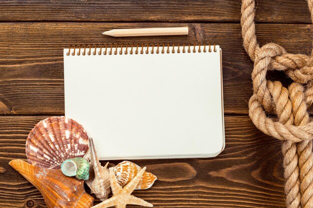 Muszle i notatnik na drewnianym stole z widokiem z miejsca na kopię