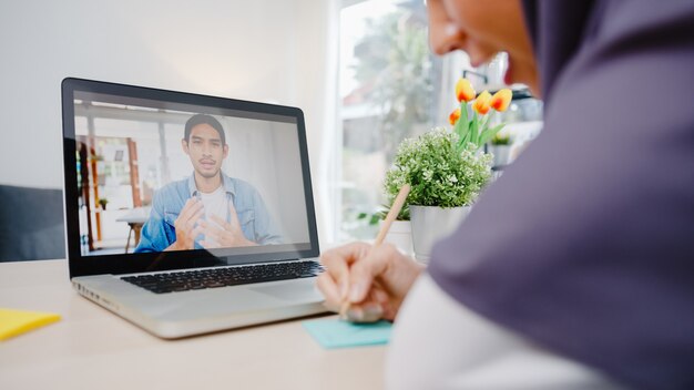 muzułmańska bizneswoman za pomocą laptopa porozmawiaj z kolegą o planie przez wideorozmowę, przeprowadź burzę mózgów podczas spotkania online, pracując zdalnie z domu w salonie.