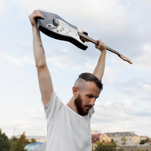 Muzyk mężczyzna trzyma gitarę elektryczną na zewnątrz