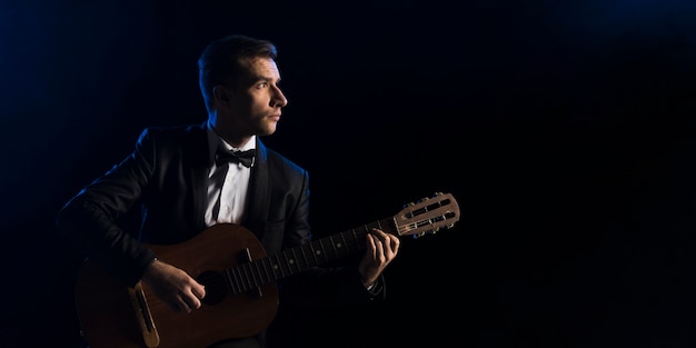 Bezpłatne zdjęcie muzyk mężczyzna z muszką, gra na gitarze klasycznej