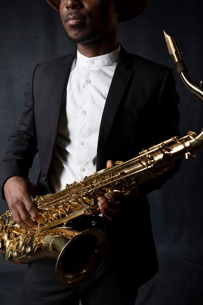 Bezpłatne zdjęcie muzyk w garniturze trzymający saksofon