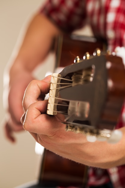 Muzyka, zbliżenie. Muzyk trzyma drewnianą gitarę