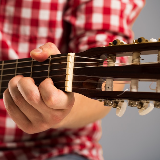 Muzyka, zbliżenie. Muzyk trzyma drewnianą gitarę