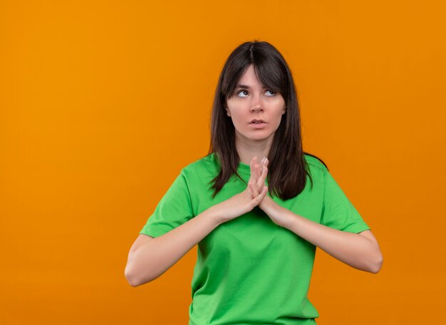Mylić młoda dziewczyna kaukaska w zielonej koszuli trzyma razem ręce na na białym tle pomarańczowy z miejsca na kopię